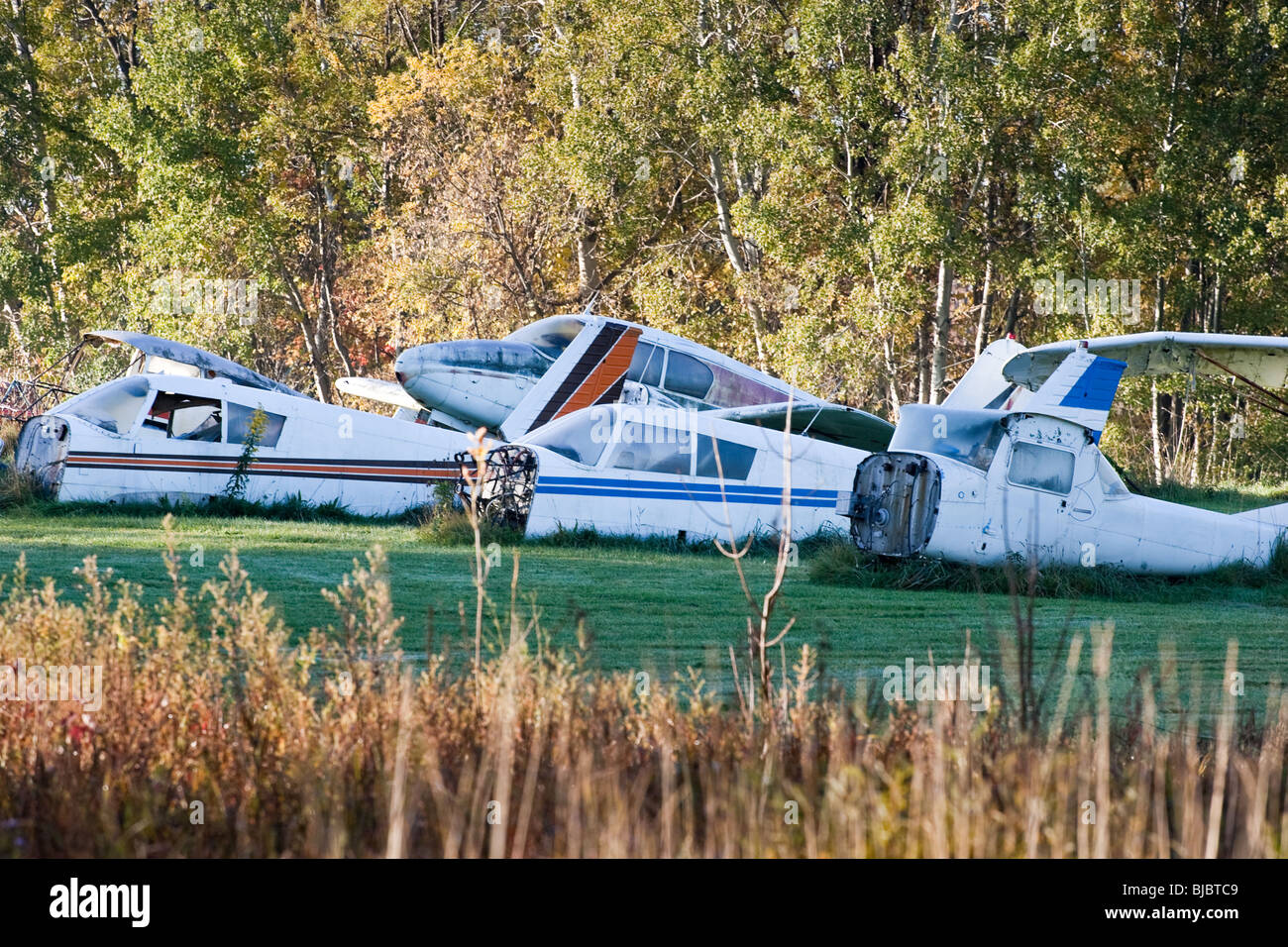 A plan graveyard in the country, showing many pieces of old prop planes in a field. Stock Photo