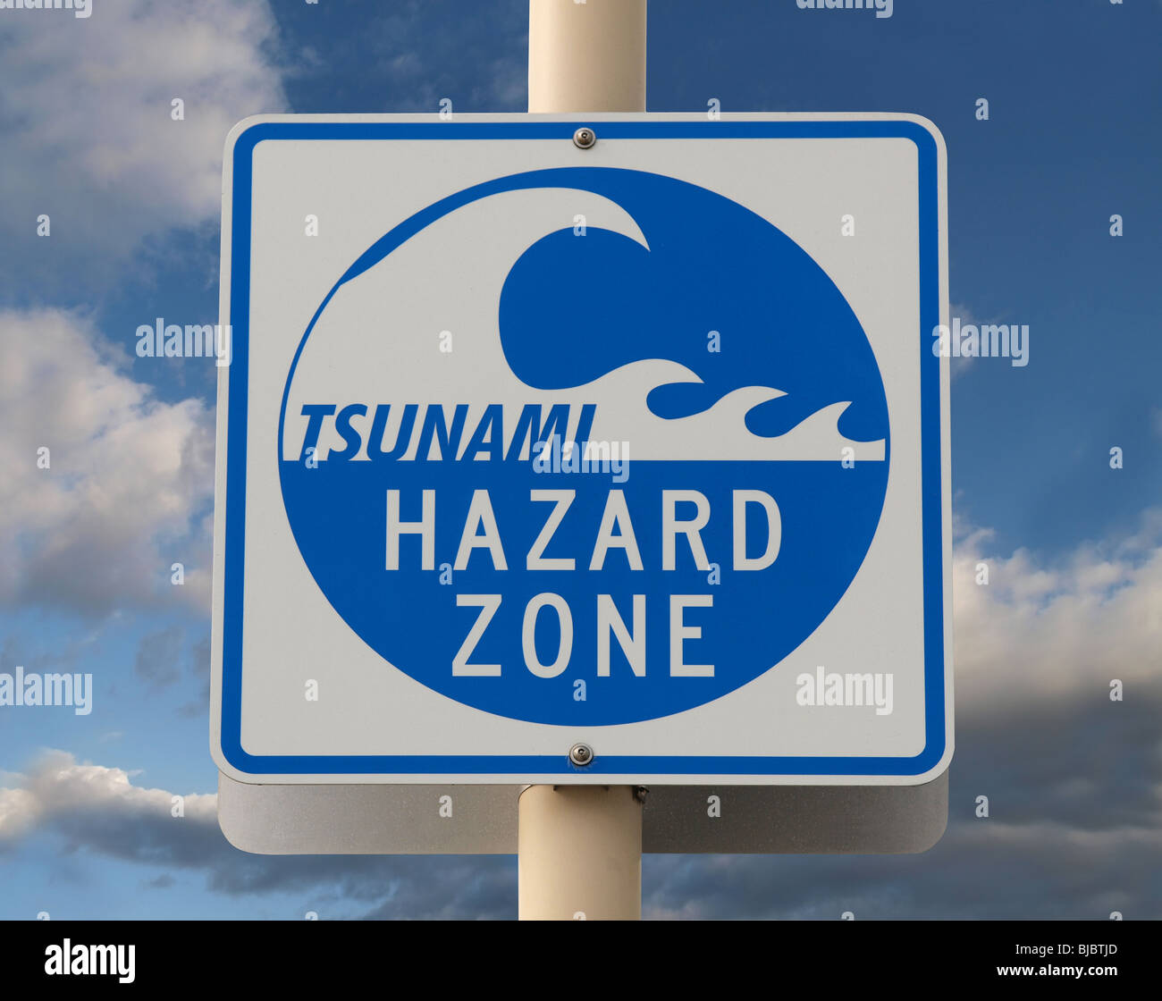 Tsunami warning sign with a cloud filled sky. Stock Photo