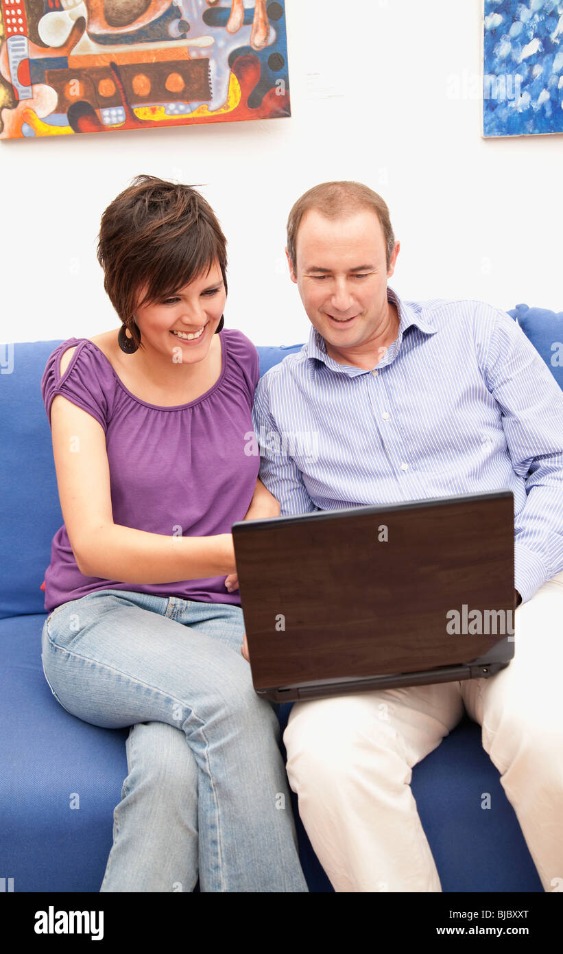 Couple on sofa using laptop together Stock Photo - Alamy