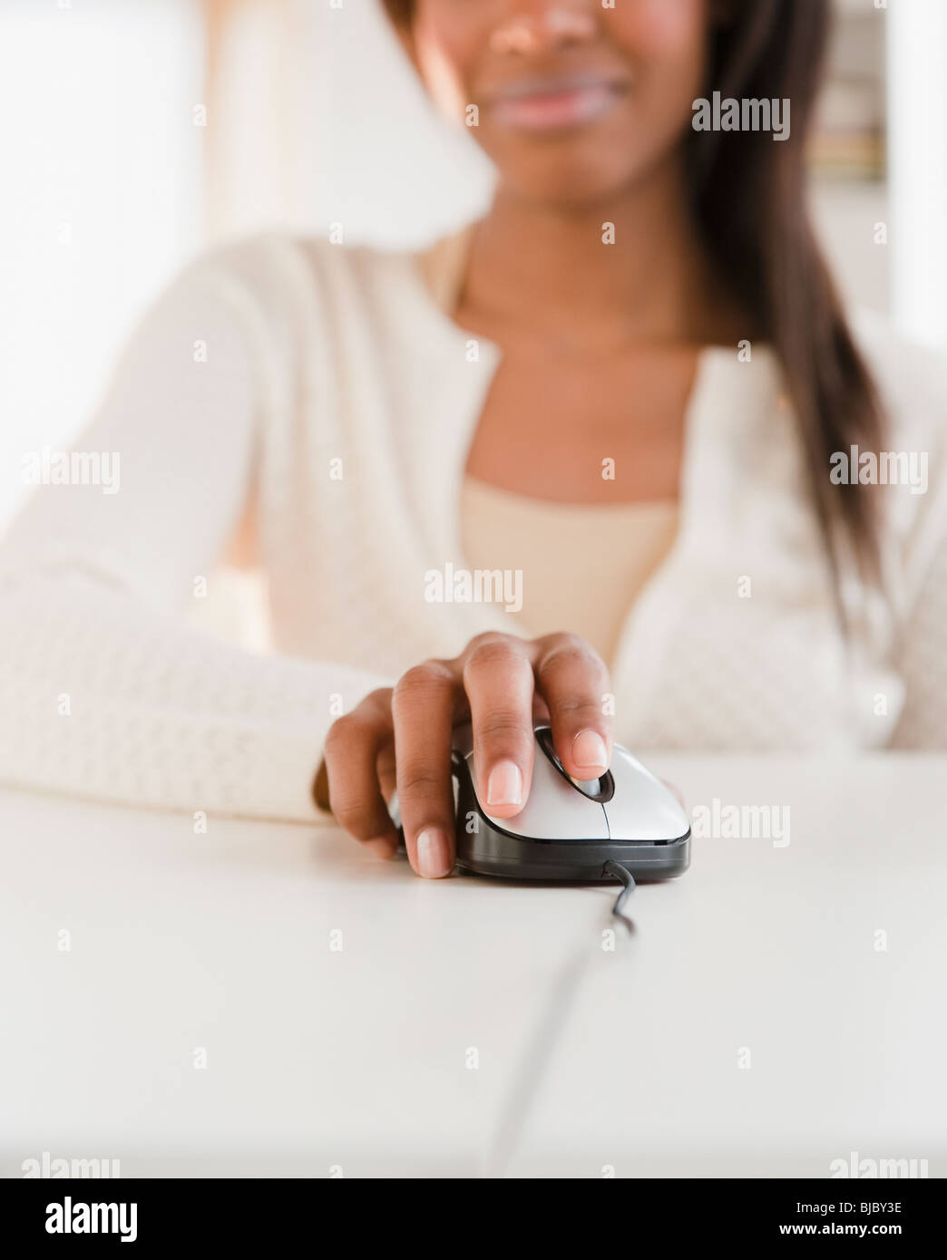 Mixed race woman using computer mouse Stock Photo