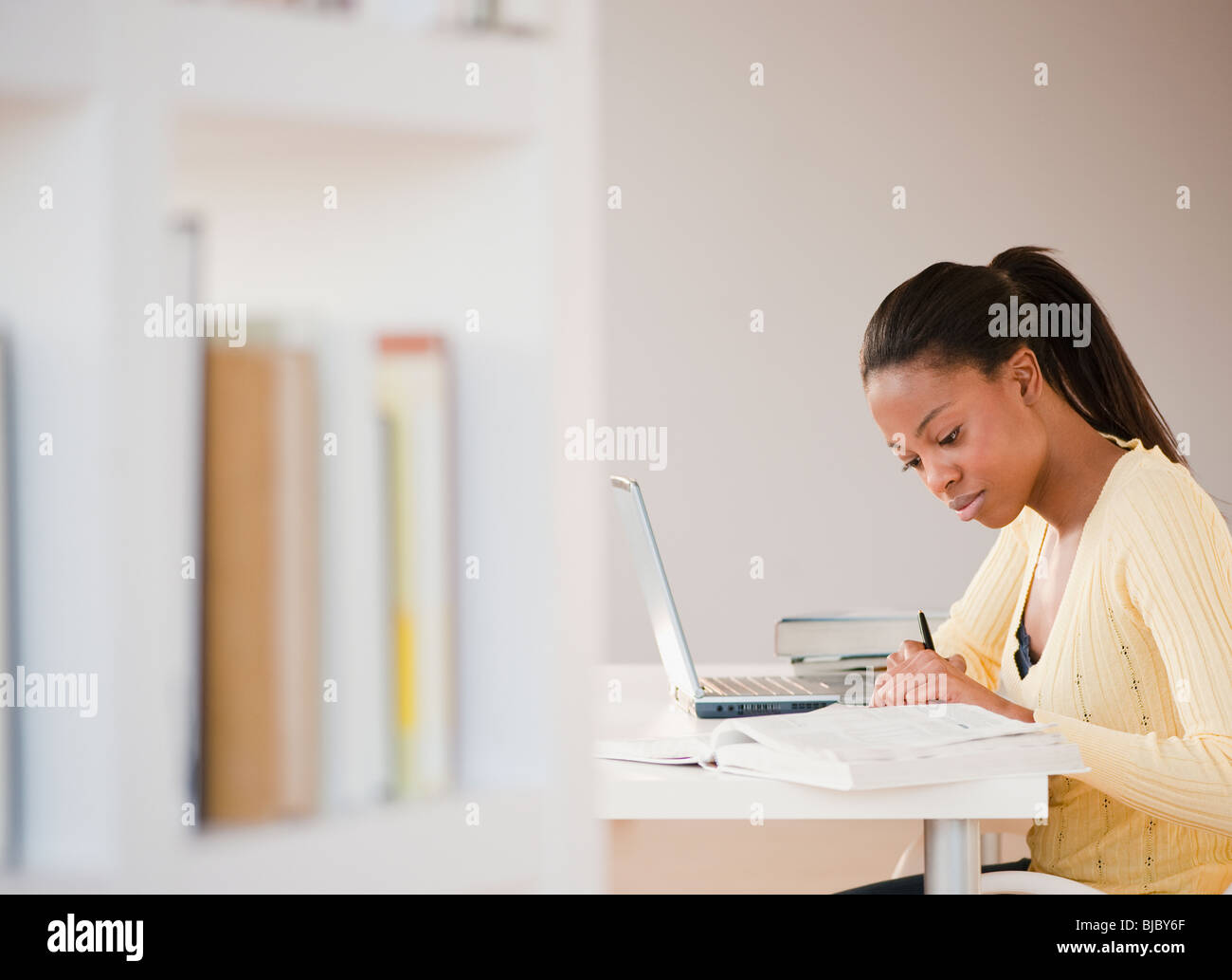 Mixed race woman doing homework with laptop Stock Photo