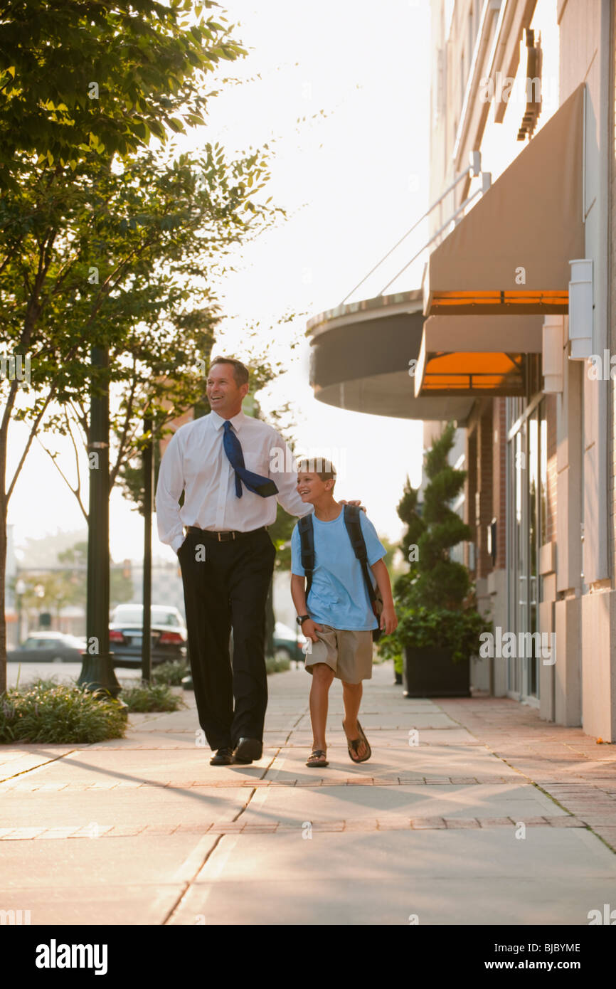 Caucasian businessman and son walking on city sidewalk Stock Photo