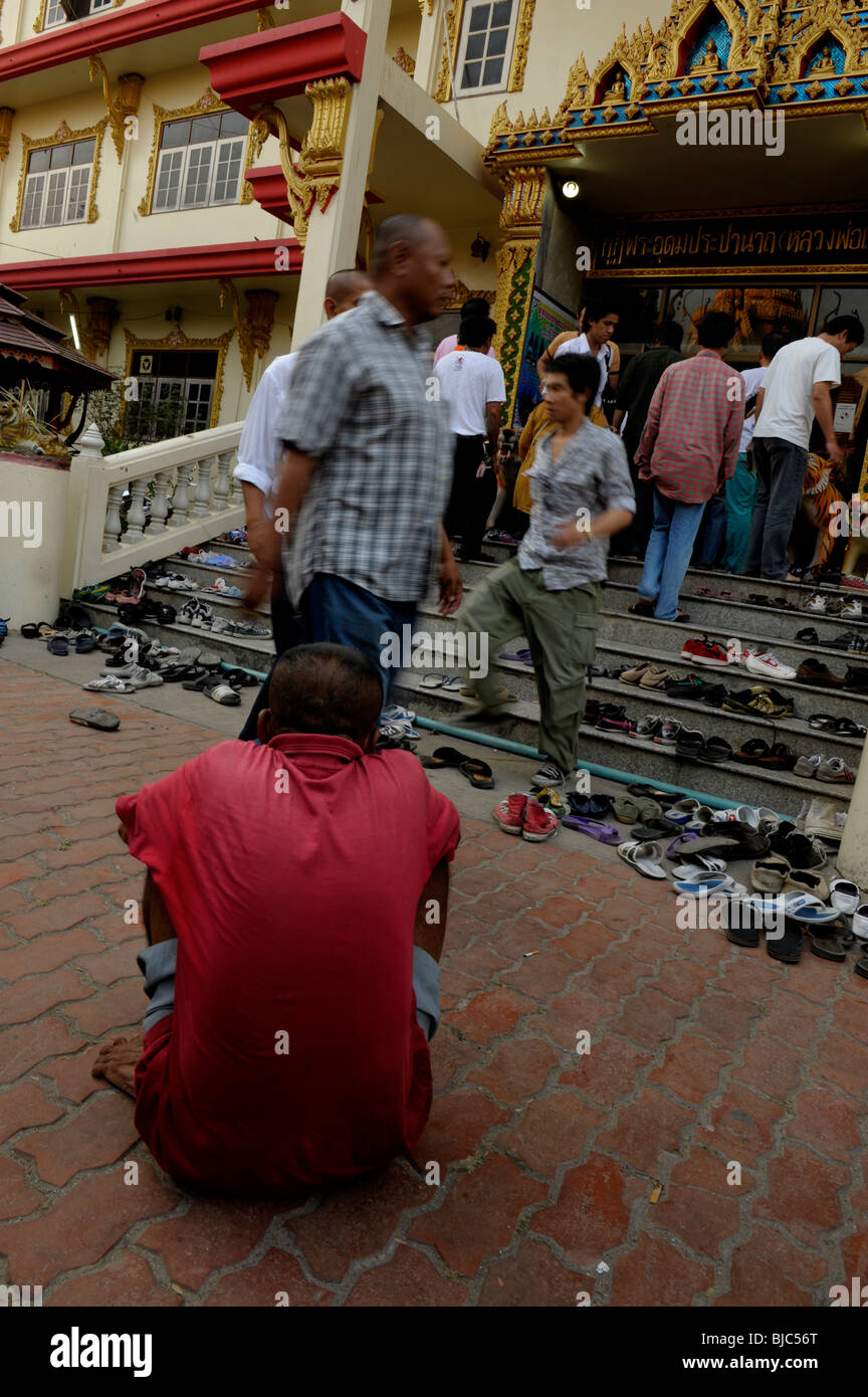 beggar keeping an eye on people shoe's for small change , wat bang phra , nakhon chiasi, thailand Stock Photo
