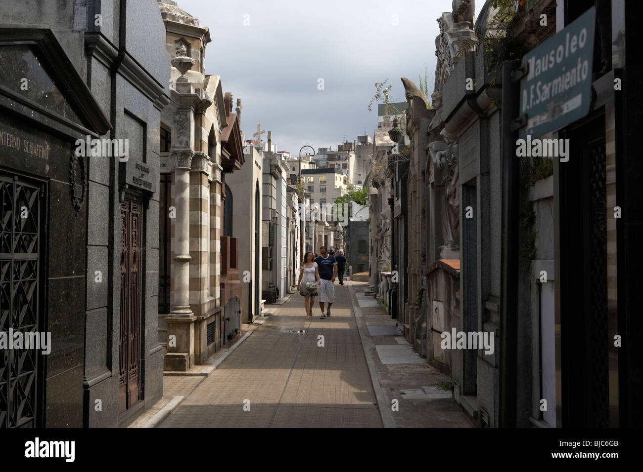 tourists walk row of older mausoleums on a street in recoleta cemetery capital federal buenos aires Stock Photo