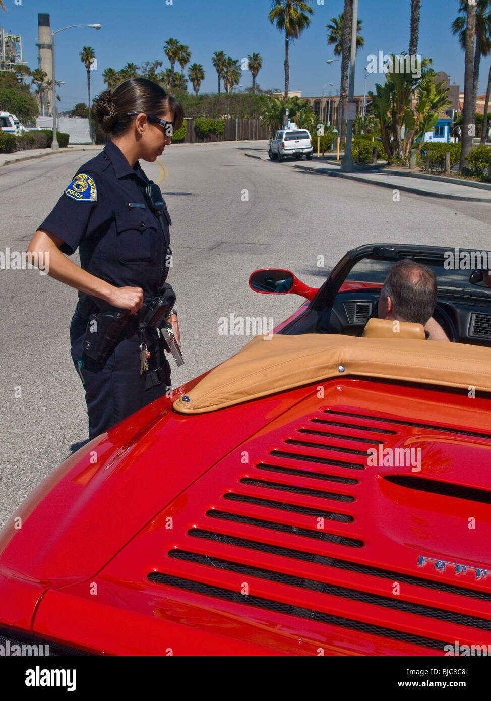 Female police officer addresses suspect driver in Ferrari Stock Photo