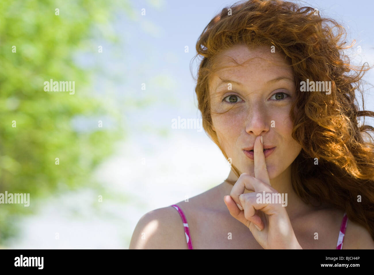 Young woman with finger on lips, portrait Stock Photo