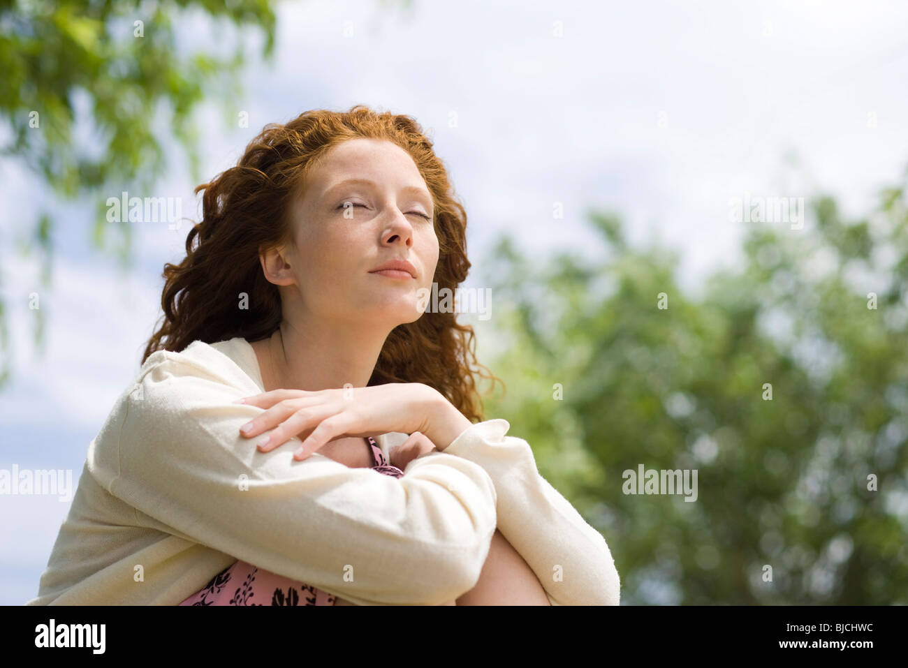 Young woman sitting outdoors with eyes closed Stock Photo - Alamy