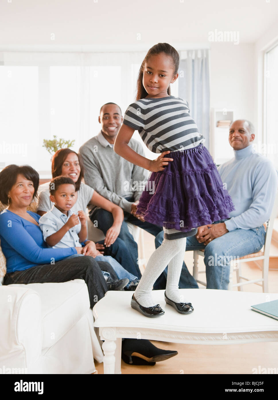 African American family watching daughter standing on table Stock Photo