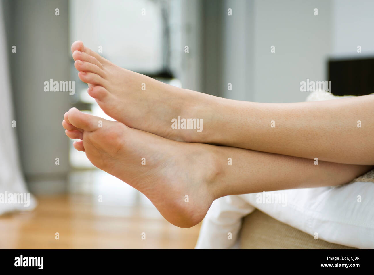 Woman's bare feet, legs crossed at ankle Stock Photo