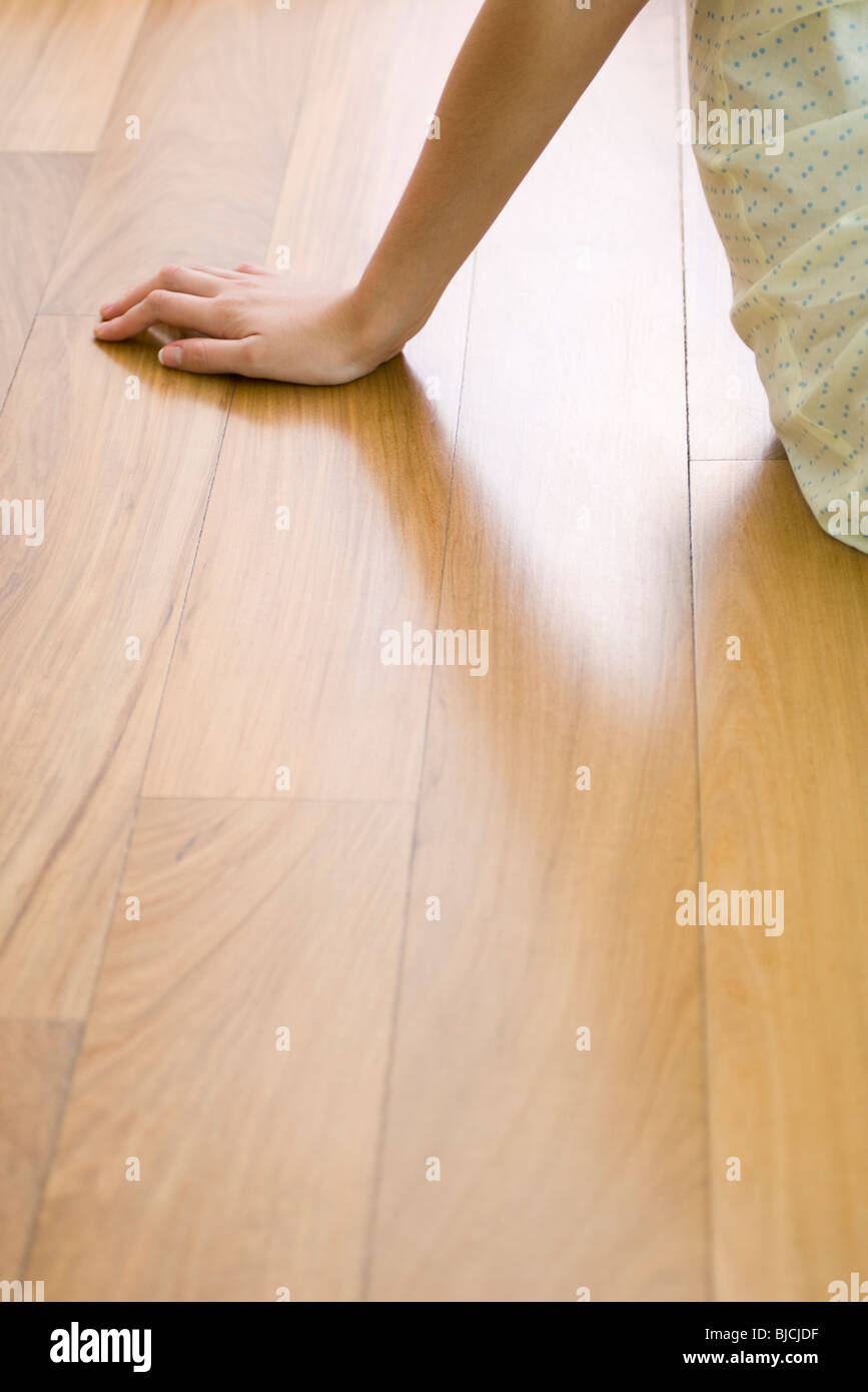Woman sitting on hardwood floor, cropped Stock Photo
