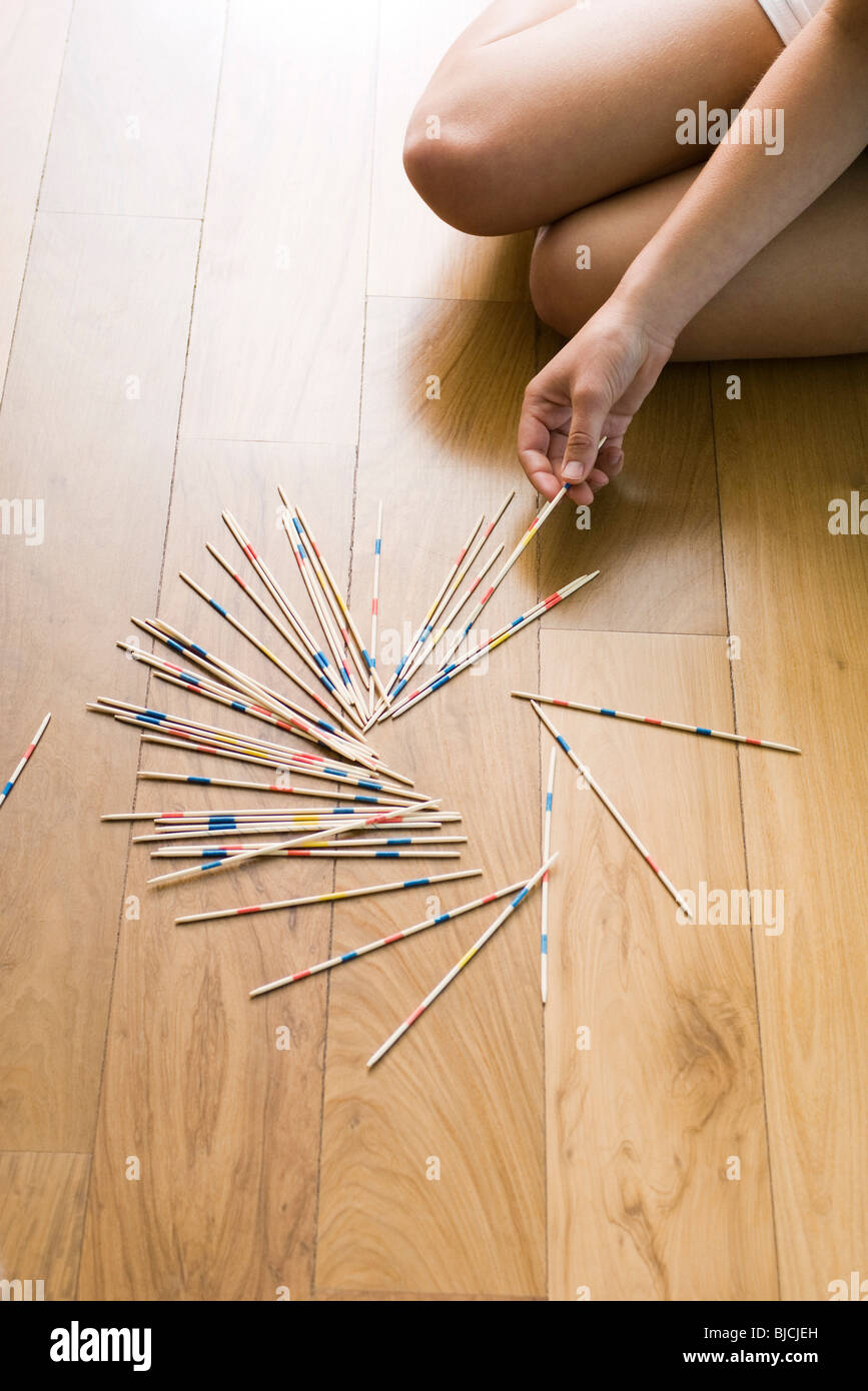 Female playing with pick up sticks on floor Stock Photo