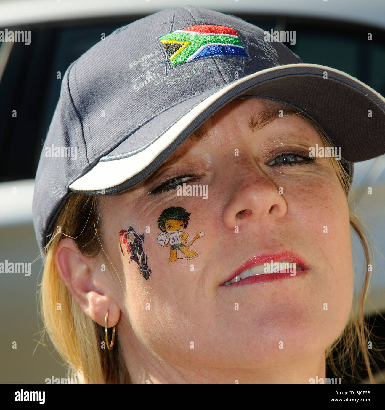 Portrait of a woman wearing a South African cap and wearing World Cup 2010 tattoos on her face Stock Photo
