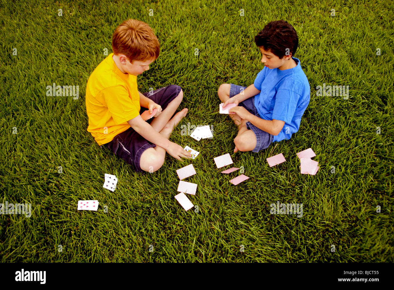 Ten-year-old boys, one Caucasian and one Iranian-American, play cards outdoors in Laguna Niguel, CA. Stock Photo