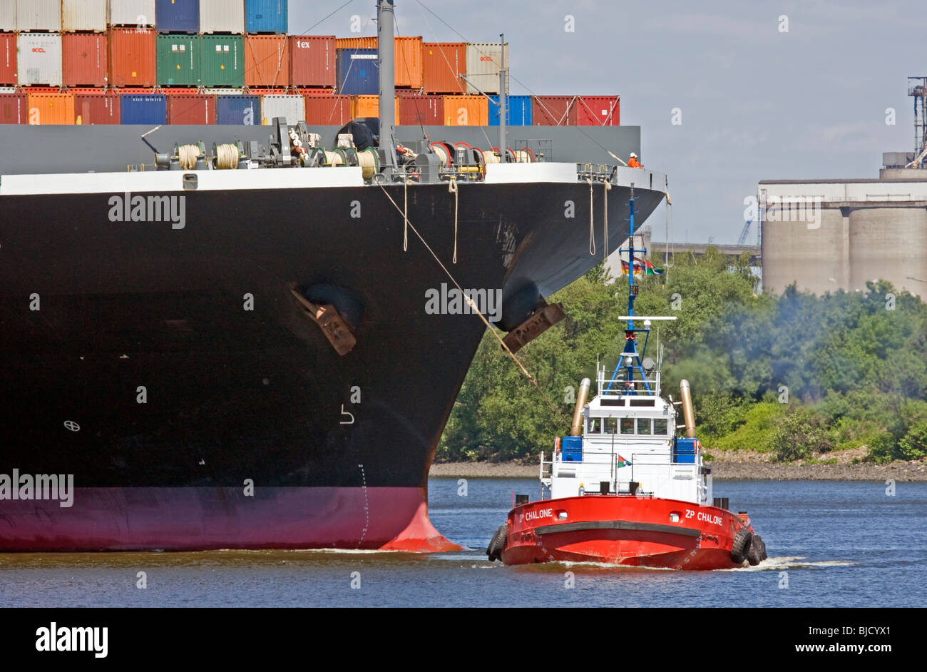 Container ship with tugboat in a harbor Stock Photo