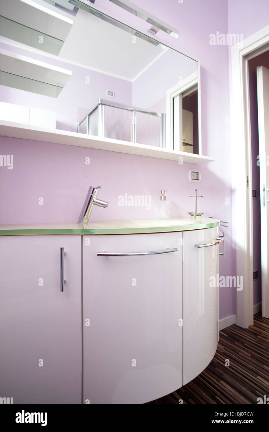 Pink bathroom wall with with shiny polished cabinets and hardwood floor Stock Photo