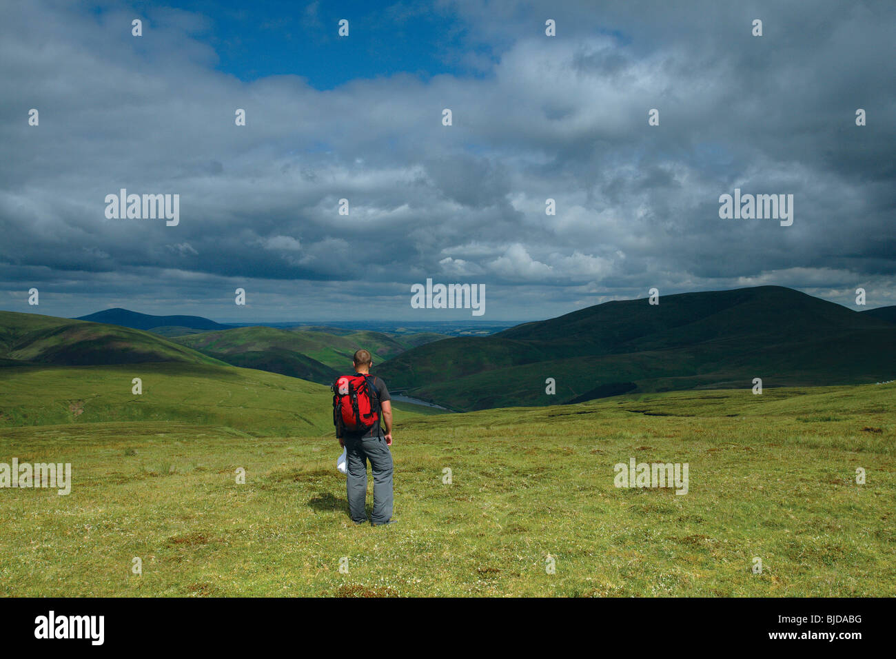 A walker looking across Culter reservoir to Culter Fell, Tinto Hill from Gathersnow Hill South Lanarkshire Scotland Stock Photo
