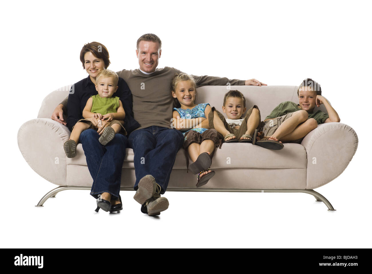 Family sitting on a couch smiling Stock Photo - Alamy