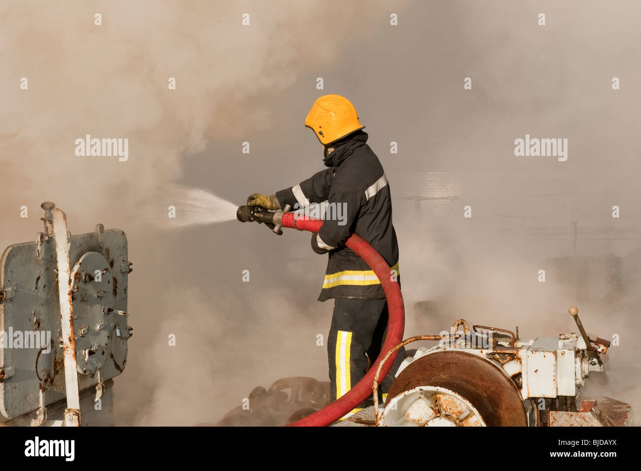 Fireman using hose on ships hold on fire Stock Photo