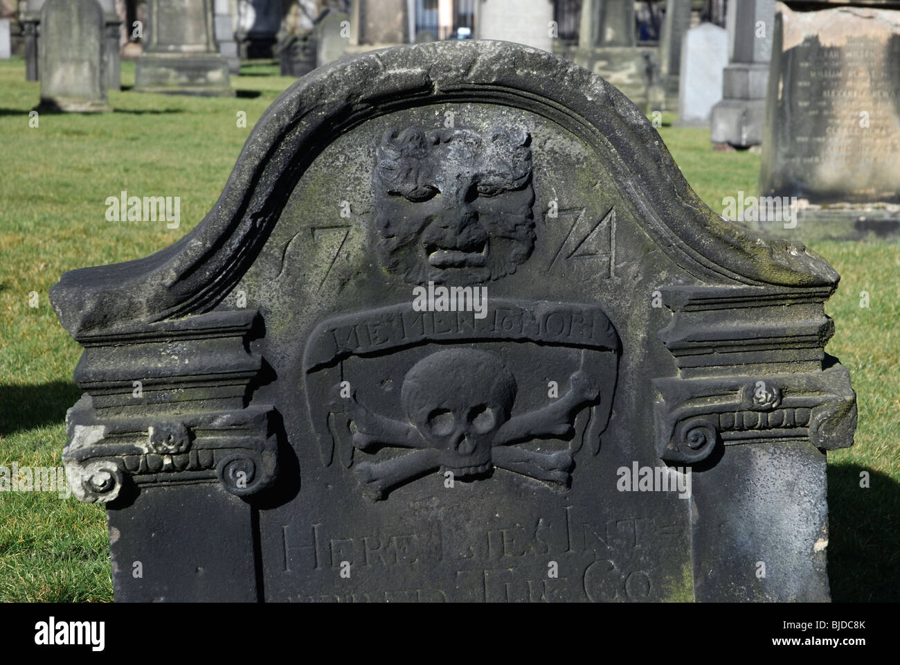 An 18th century headstone with a 'green man' and skull and crossbones in South Leith Parish churchyard, Leith, Edinburgh, Scotland. Stock Photo