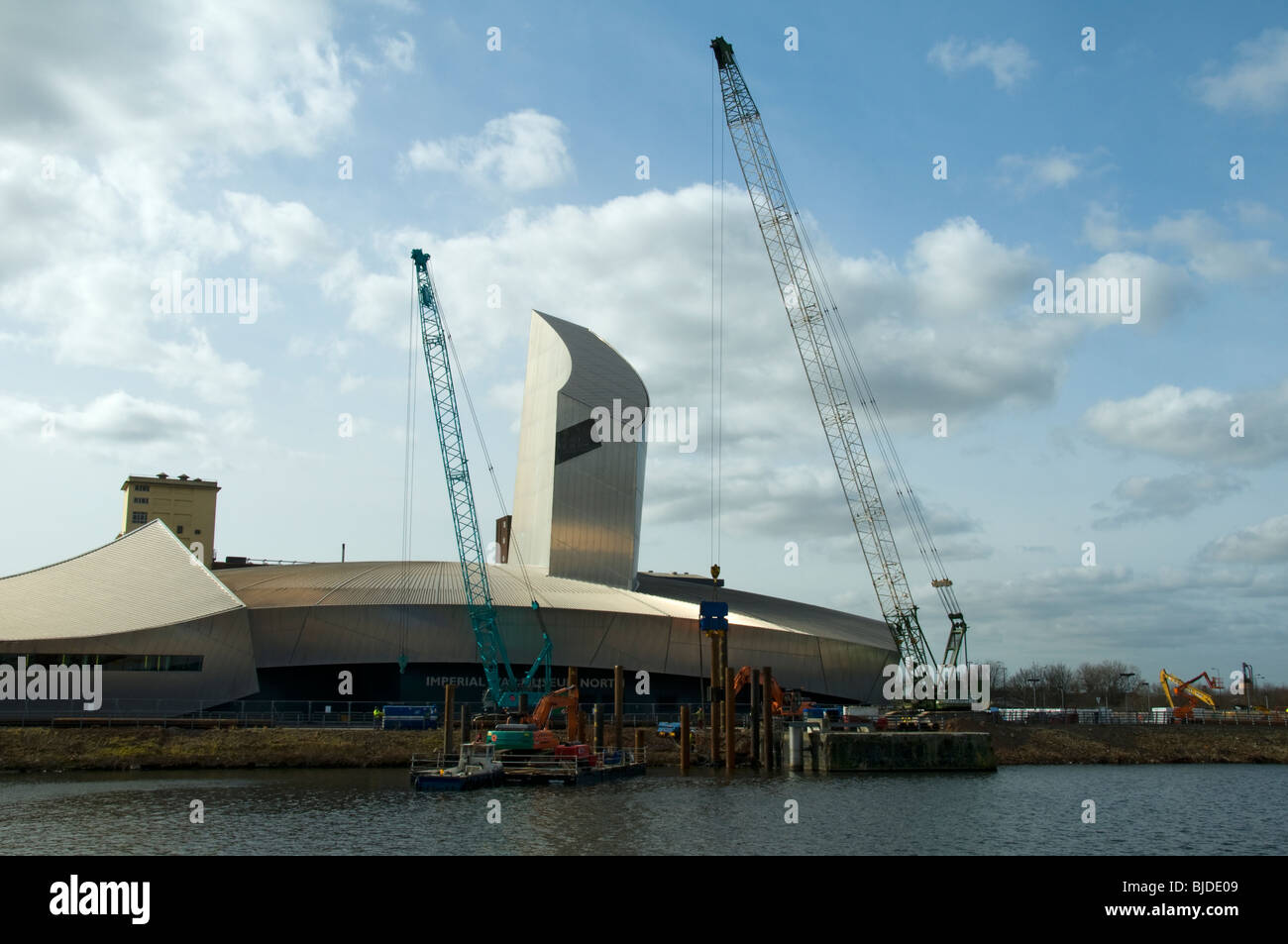 Pile driving operation, using a vibratory pile driver, outside the Imperial War Museum North at Salford Quays, Manchester, UK Stock Photo