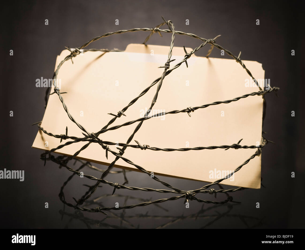 Manila file folder surrounded by barbed wire. Stock Photo