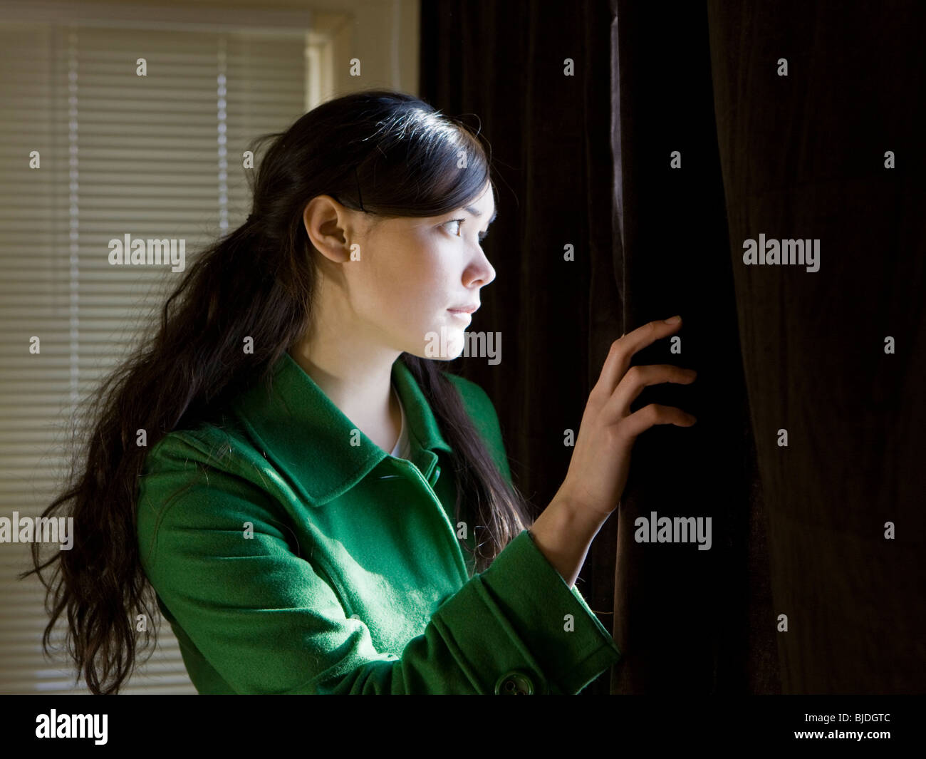 young woman looking out a window Stock Photo