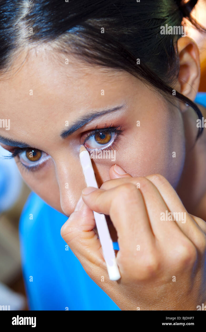 Woman applying white eye liner Stock Photo