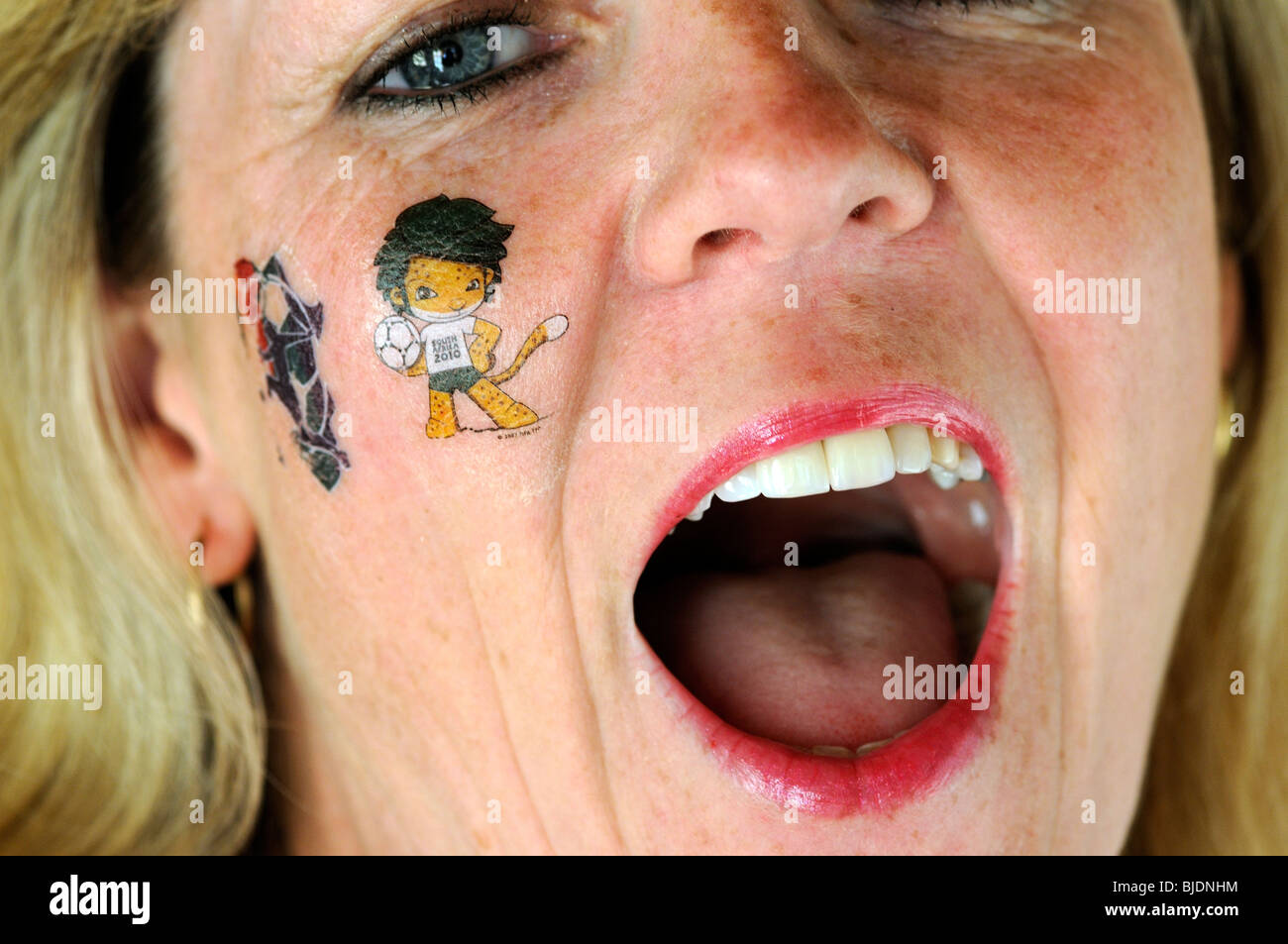 Female soccer supporter wearing a tattoo of Zakumi the host nations mascot and the FIFA logo 'Football is Life' emblem for World Stock Photo
