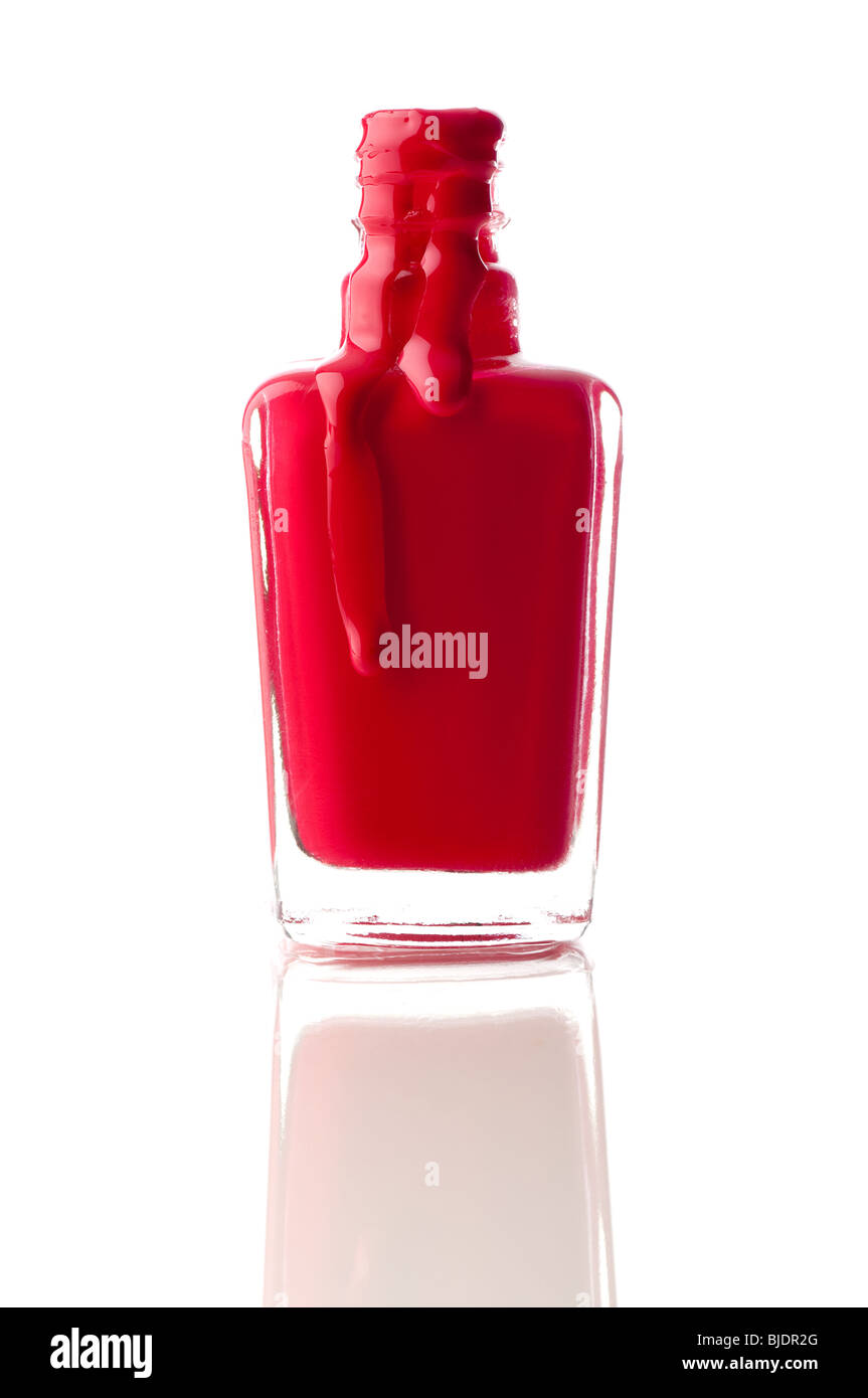 Vertical image of red nail polish running out of a container on a reflective surface Stock Photo