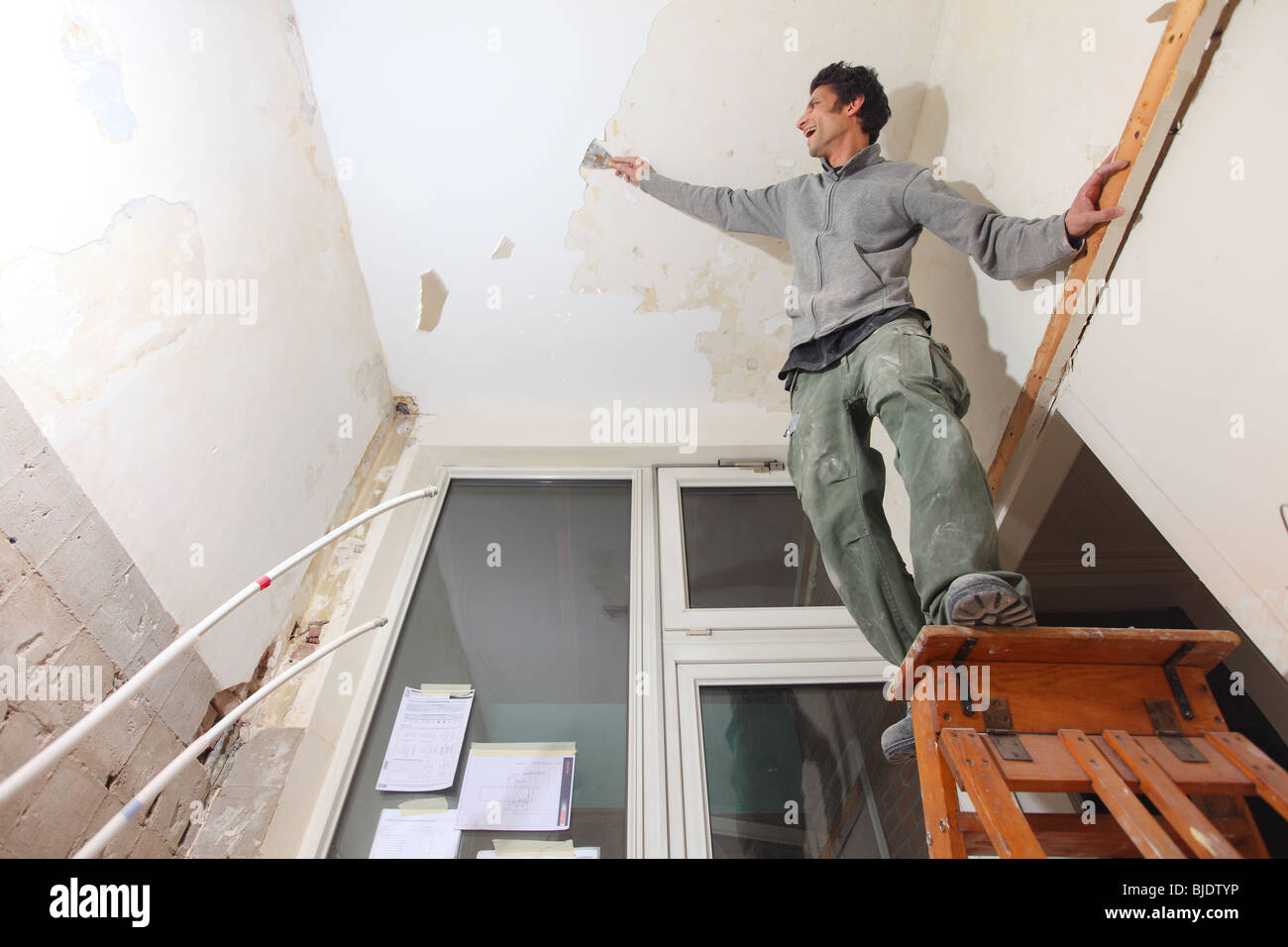 Man Working In Kitchen And Removing Old Paint Of Ceiling With