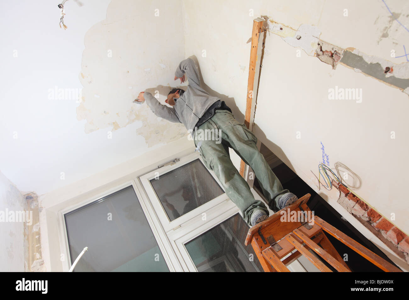Man Working In Kitchen And Removing Old Paint Of Ceiling With