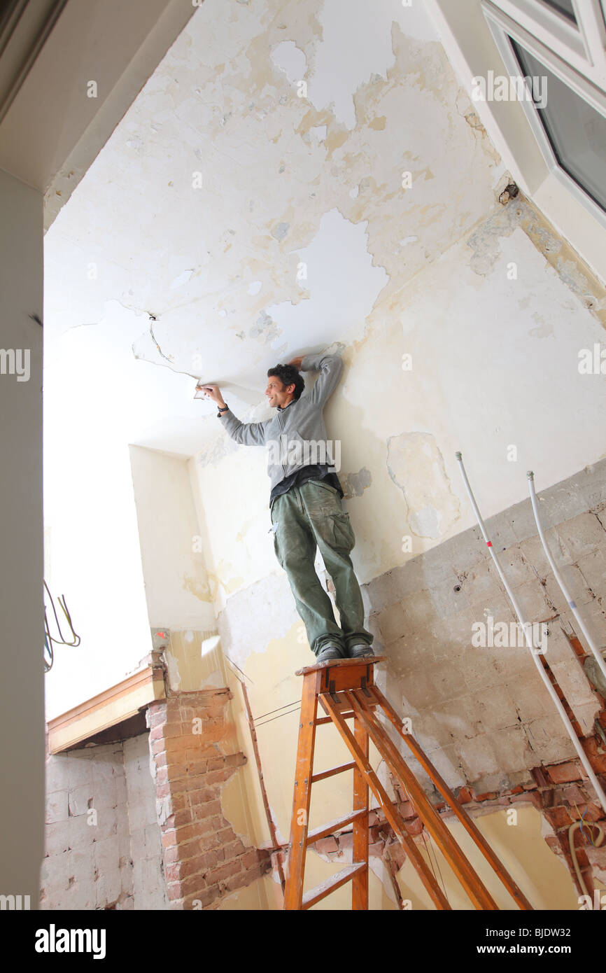 Man Working In Kitchen And Removing Old Paint Of Ceiling With
