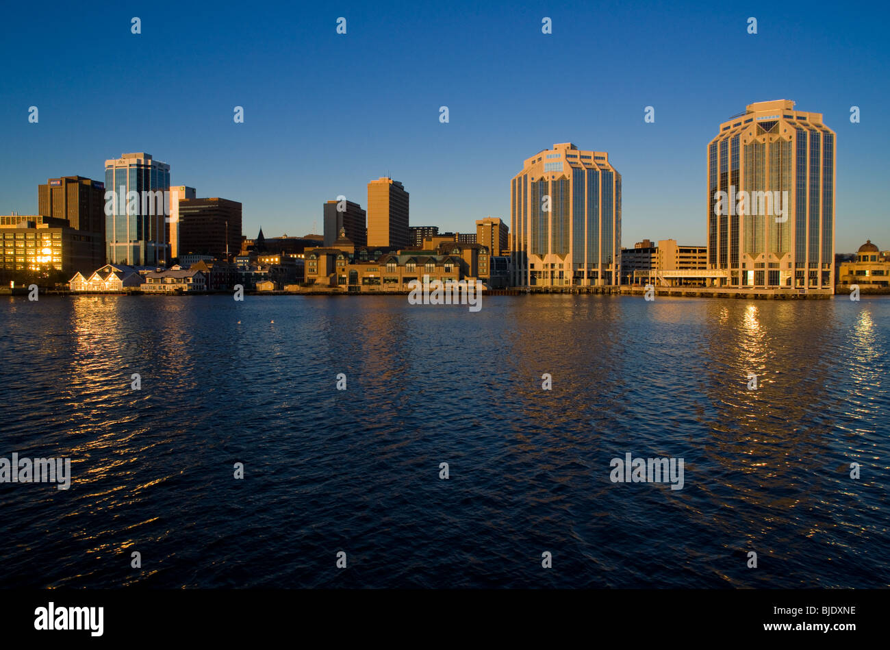 The skyline of Halifax, Nova Scotia, just after sunrise. Sunlight reflecting from multiple buildings sparkles on the water. Stock Photo