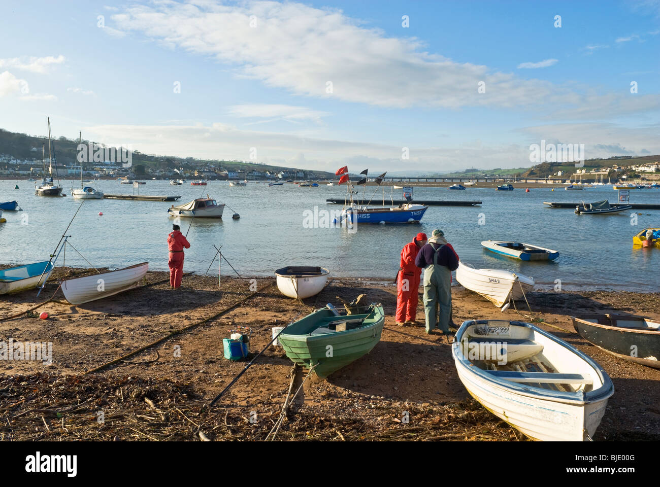 Fishermen fishing onshore between moored boats. Teignmouth, Devon, England UK Stock Photo