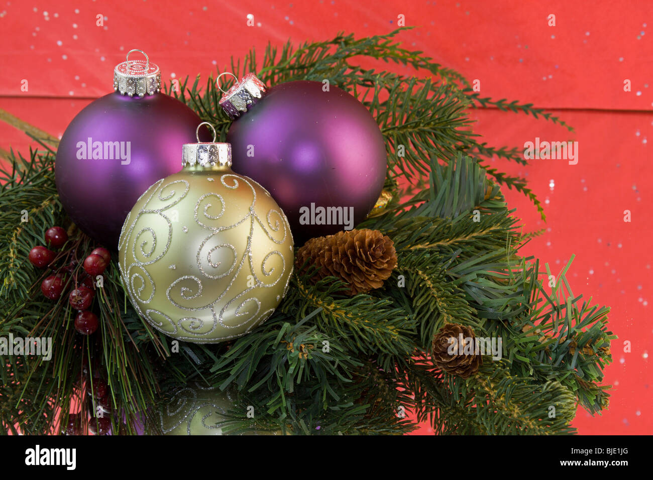 gold scroll pattern ornament, with purple baubles on fir branch with pinecone Stock Photo