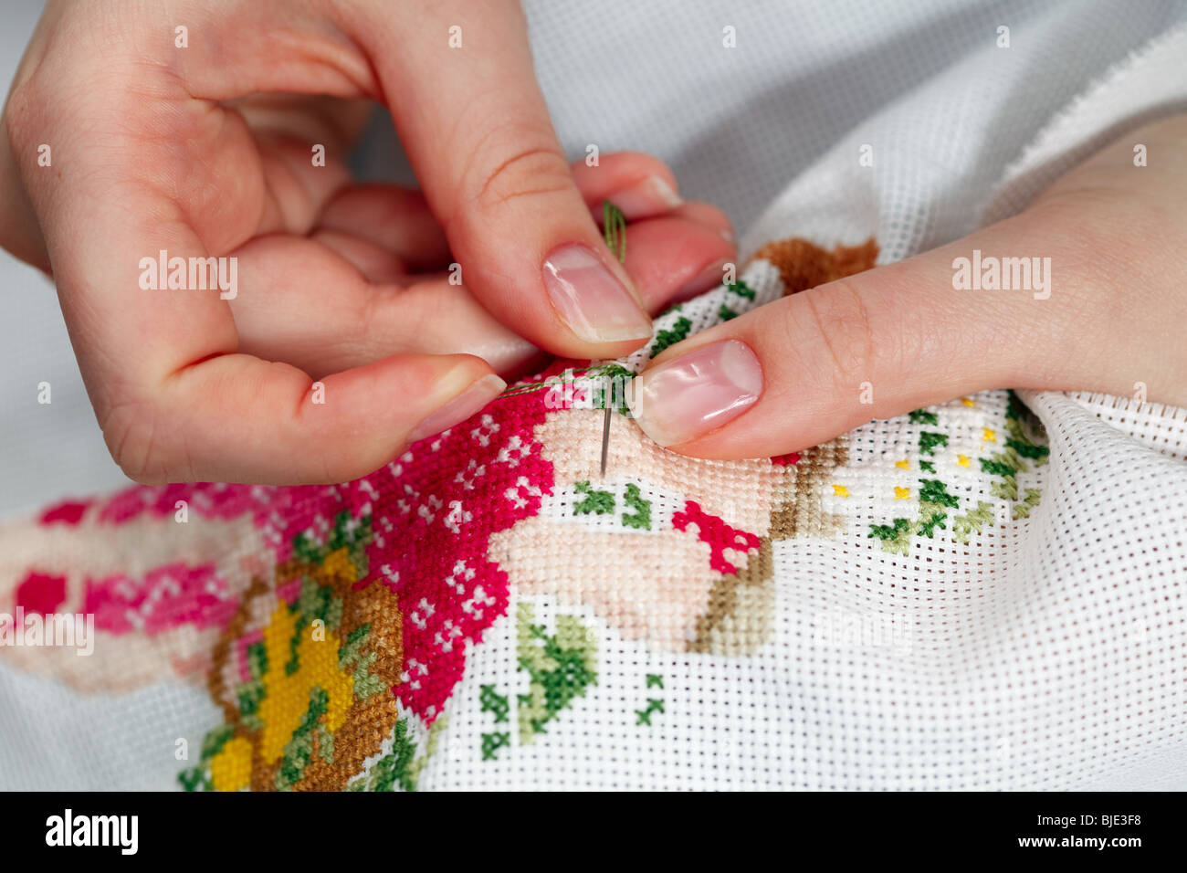 Fingers of young women, cross embroidery. Stock Photo