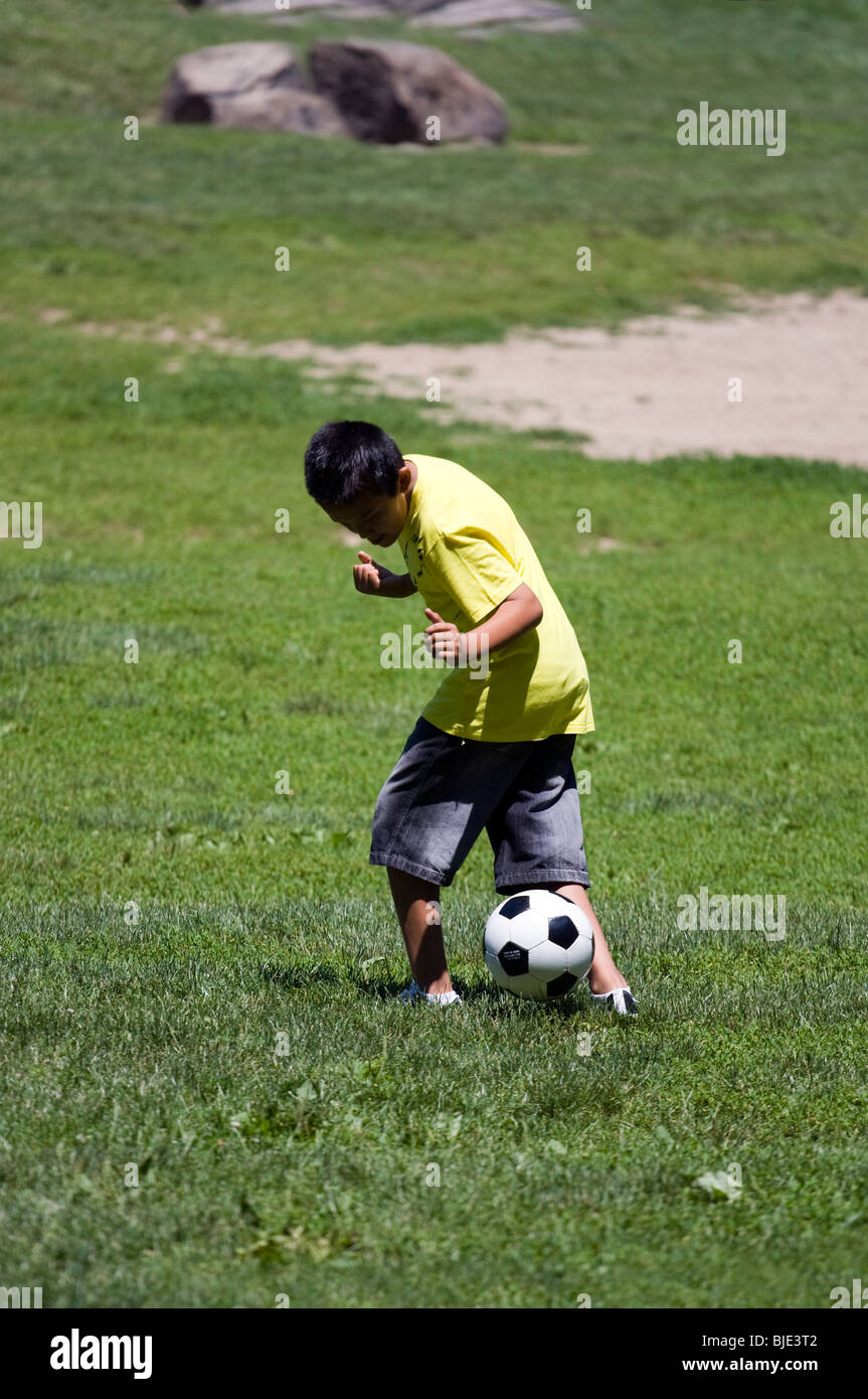 Young Asian Boy playing with soccer ball in city park. Stock Photo