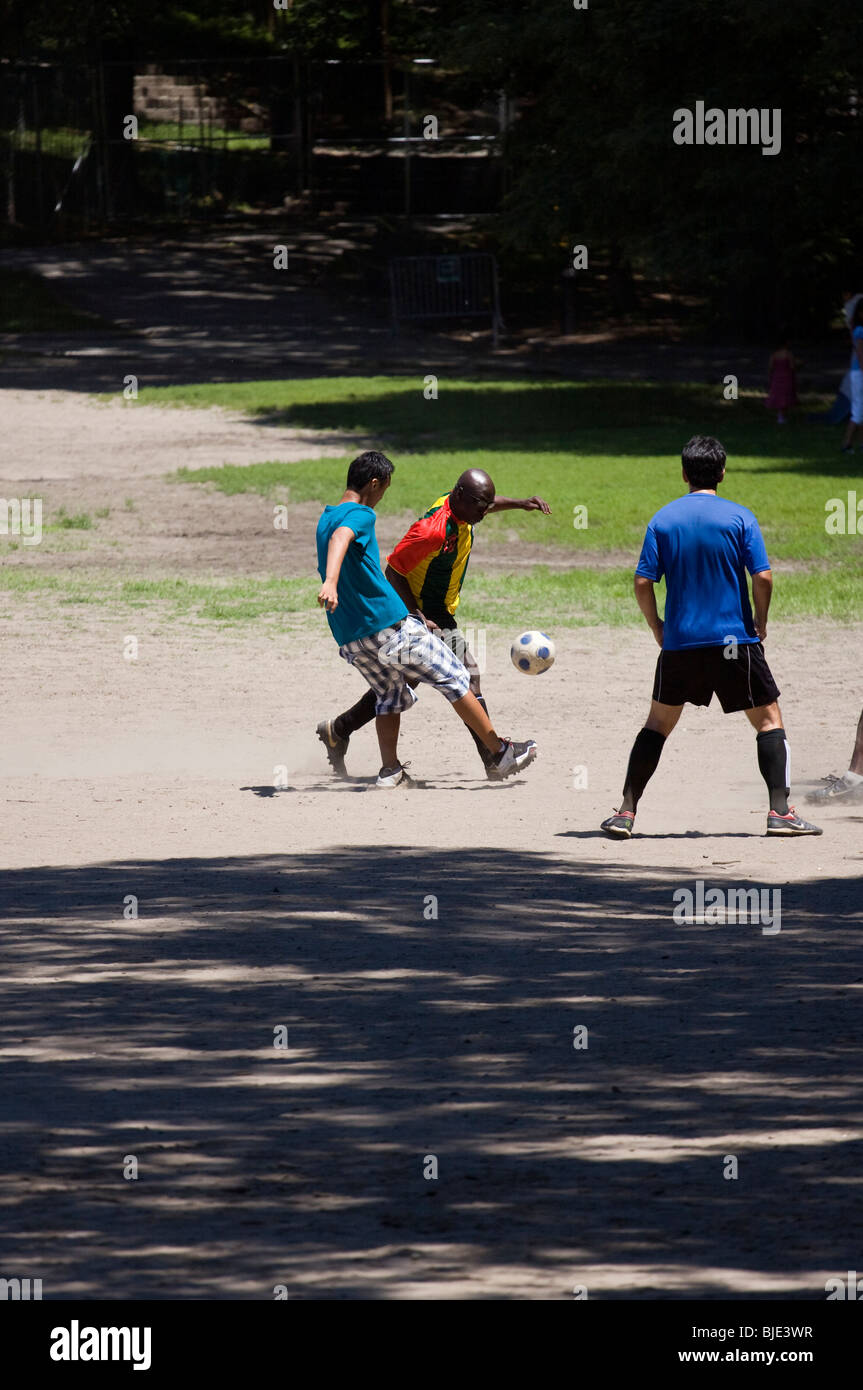 Three men playing with soccer ball in city park. Stock Photo