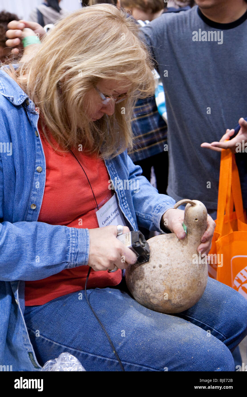 An exhibitor crafting a piece of wood into a musical instrument Stock Photo