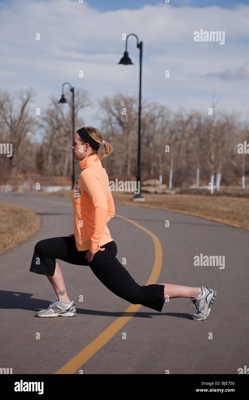 Woman runner stretching on a path in city park Stock Photo