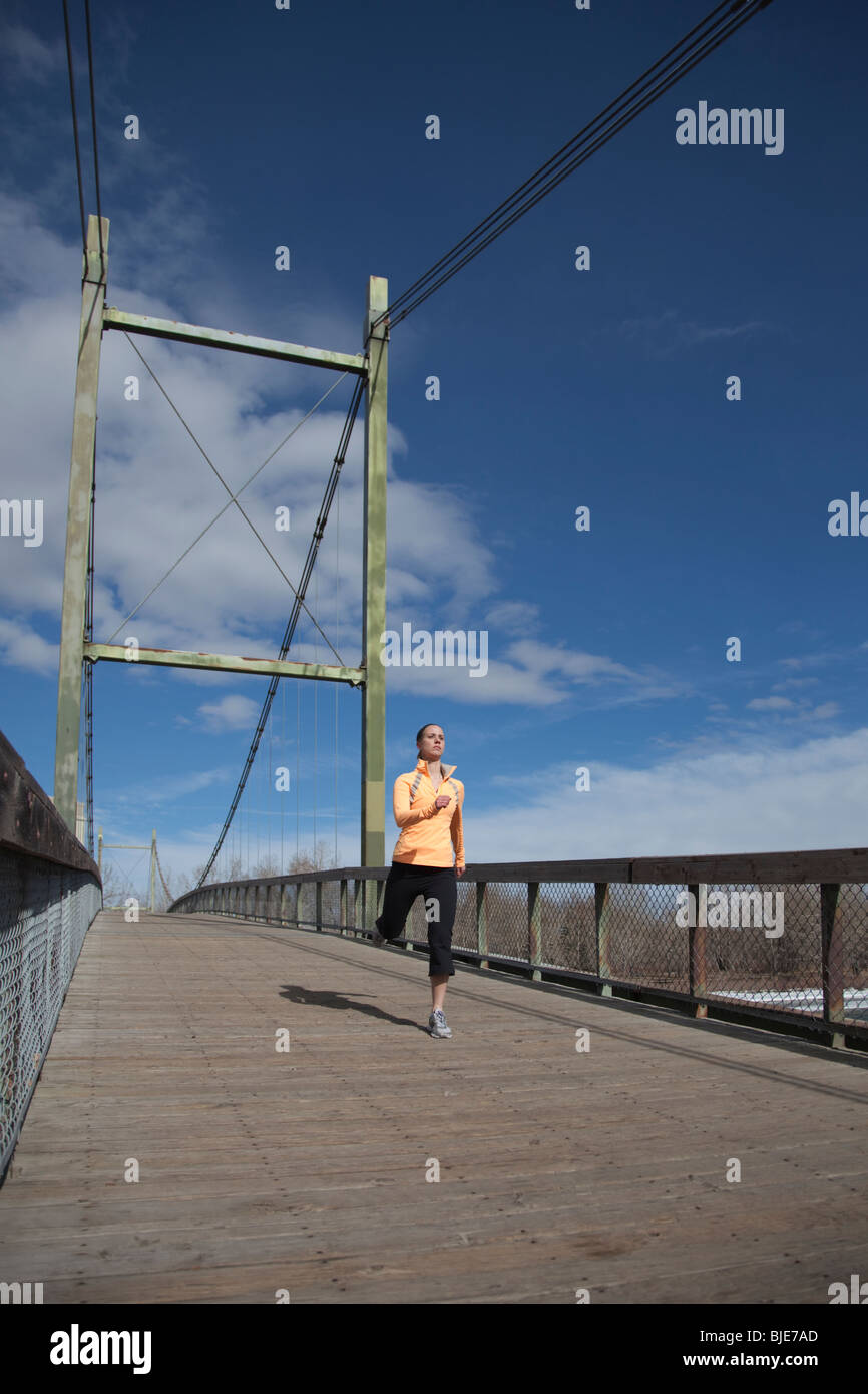 Woman running across bridge in city park Stock Photo Alamy