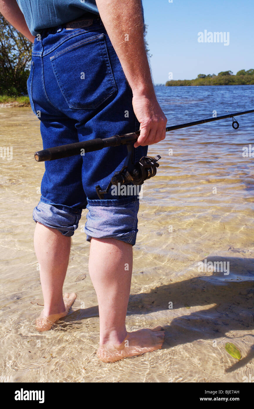 https://c8.alamy.com/comp/BJE7AH/fisherman-standing-in-shallow-water-holding-fishing-rod-and-reel-blue-BJE7AH.jpg