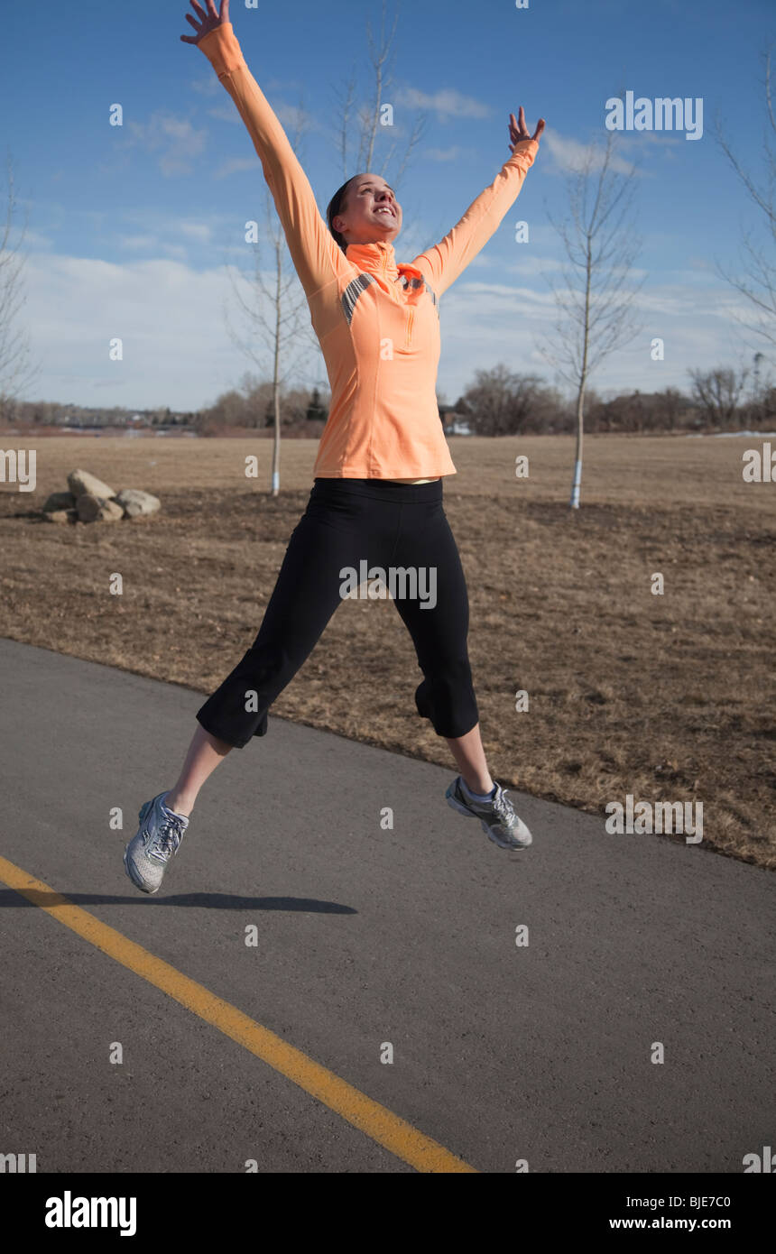Woman jumping for joy in park Stock Photo
