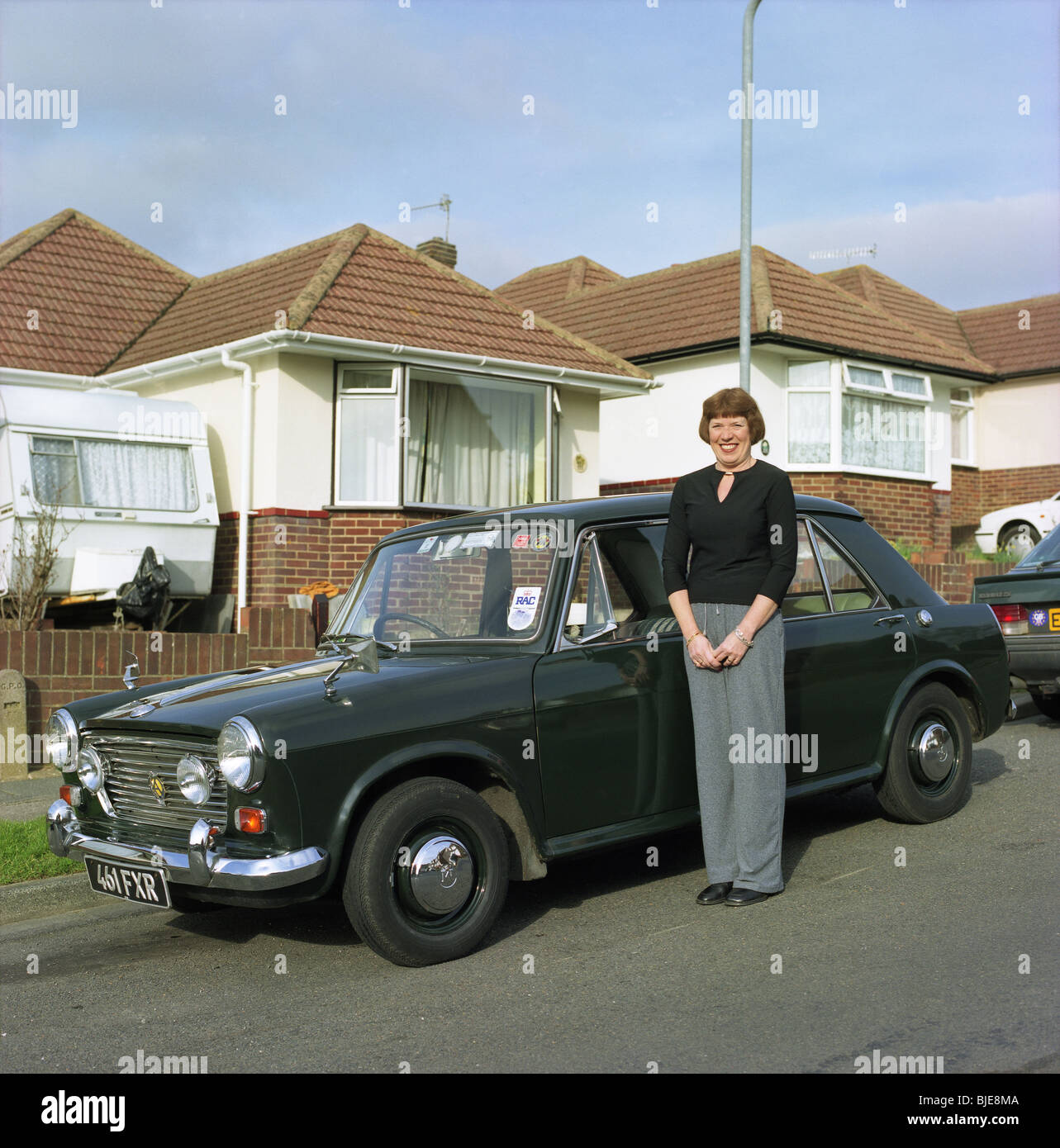 Woman standing next to a 1960s Morris 1100 saloon car Stock Photo