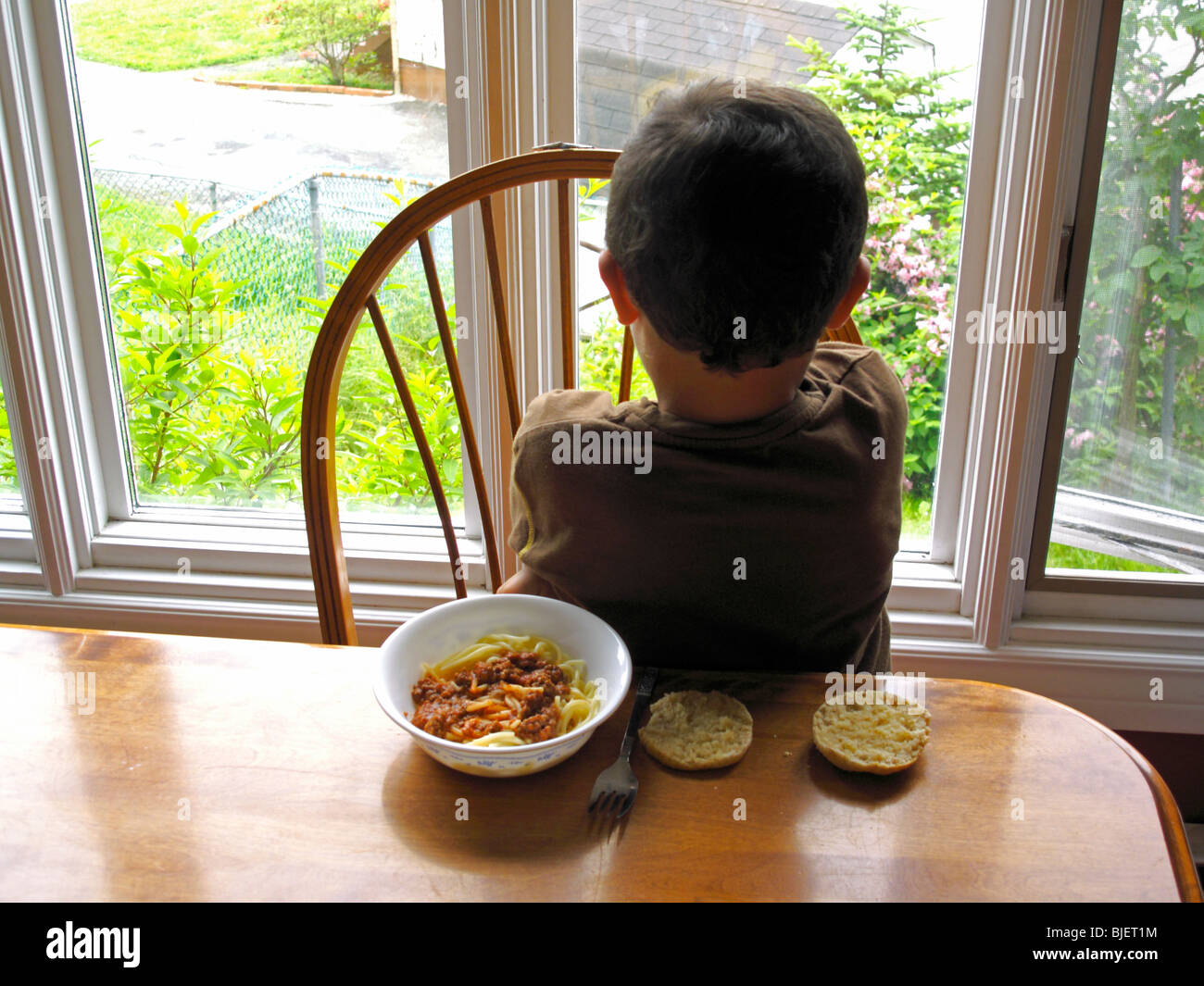 a four year old child having a temper tantrum at the dinner table and being defiant or a boy not eating because he is upset Stock Photo