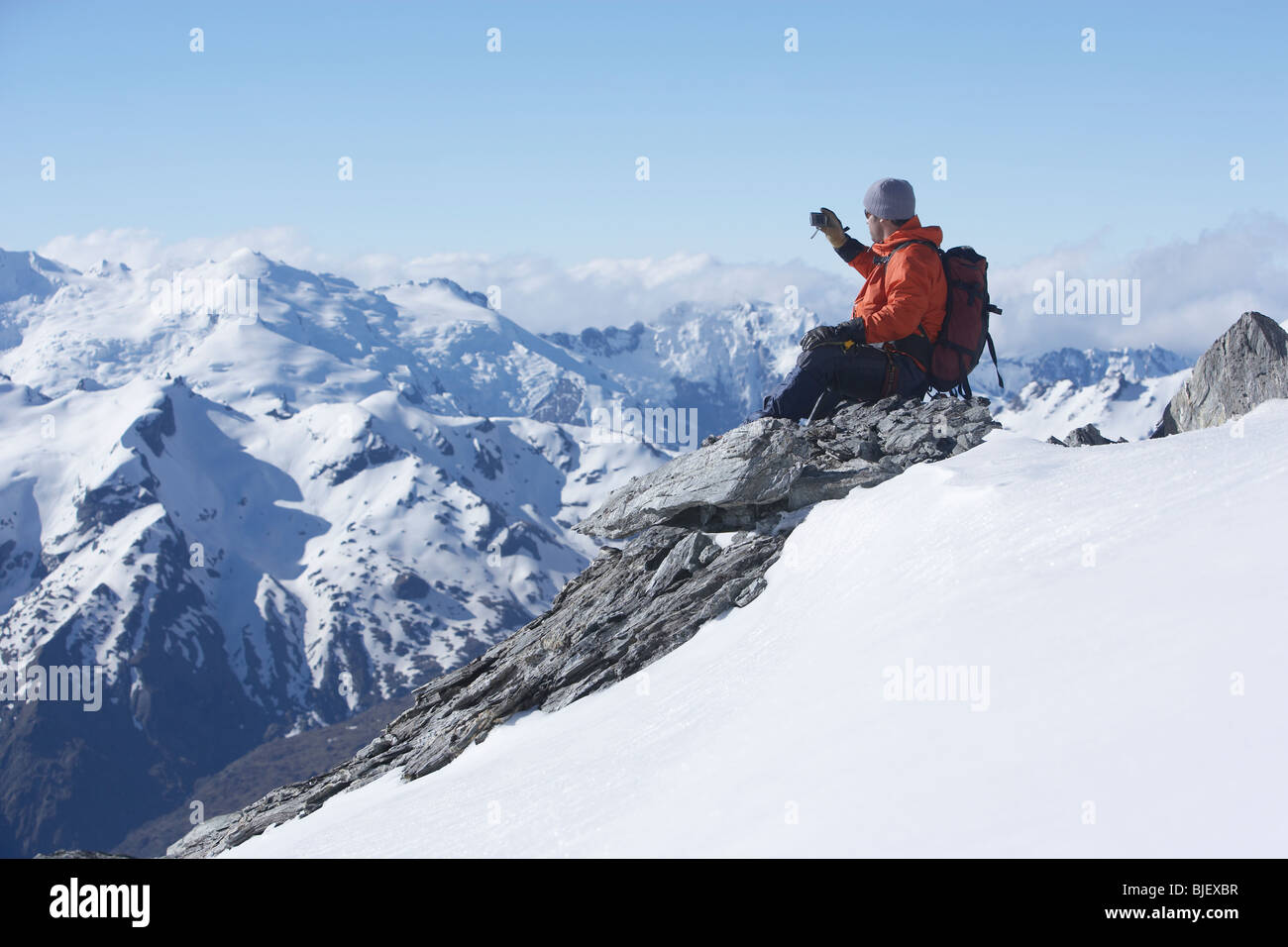 Mountain climber taking picture on mountain peak Stock Photo