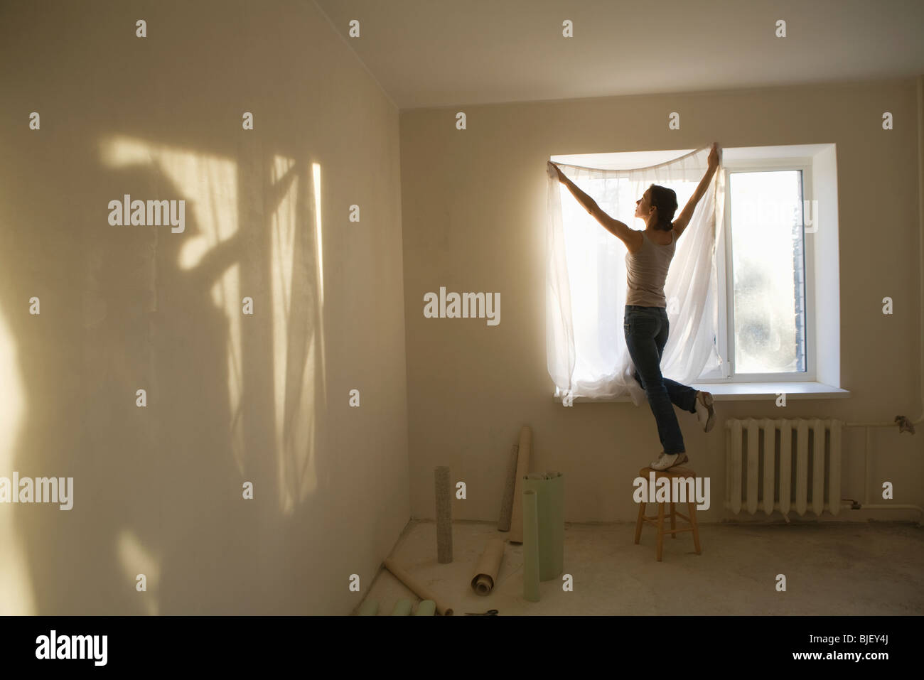 Woman fitting curtains in new apartment Stock Photo