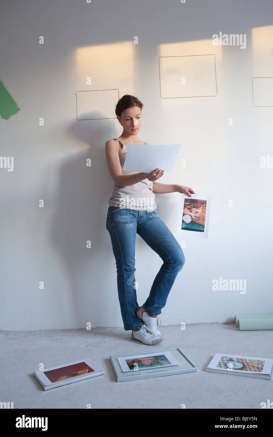 Woman decides on pictures to mount in new apartment Stock Photo