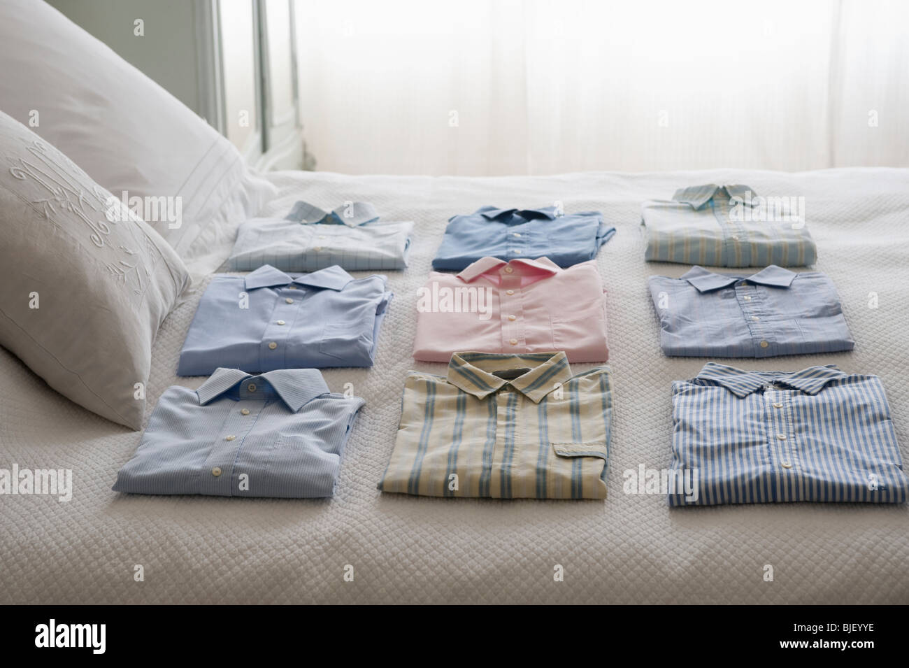 Clean shirts ordered on a bed Stock Photo