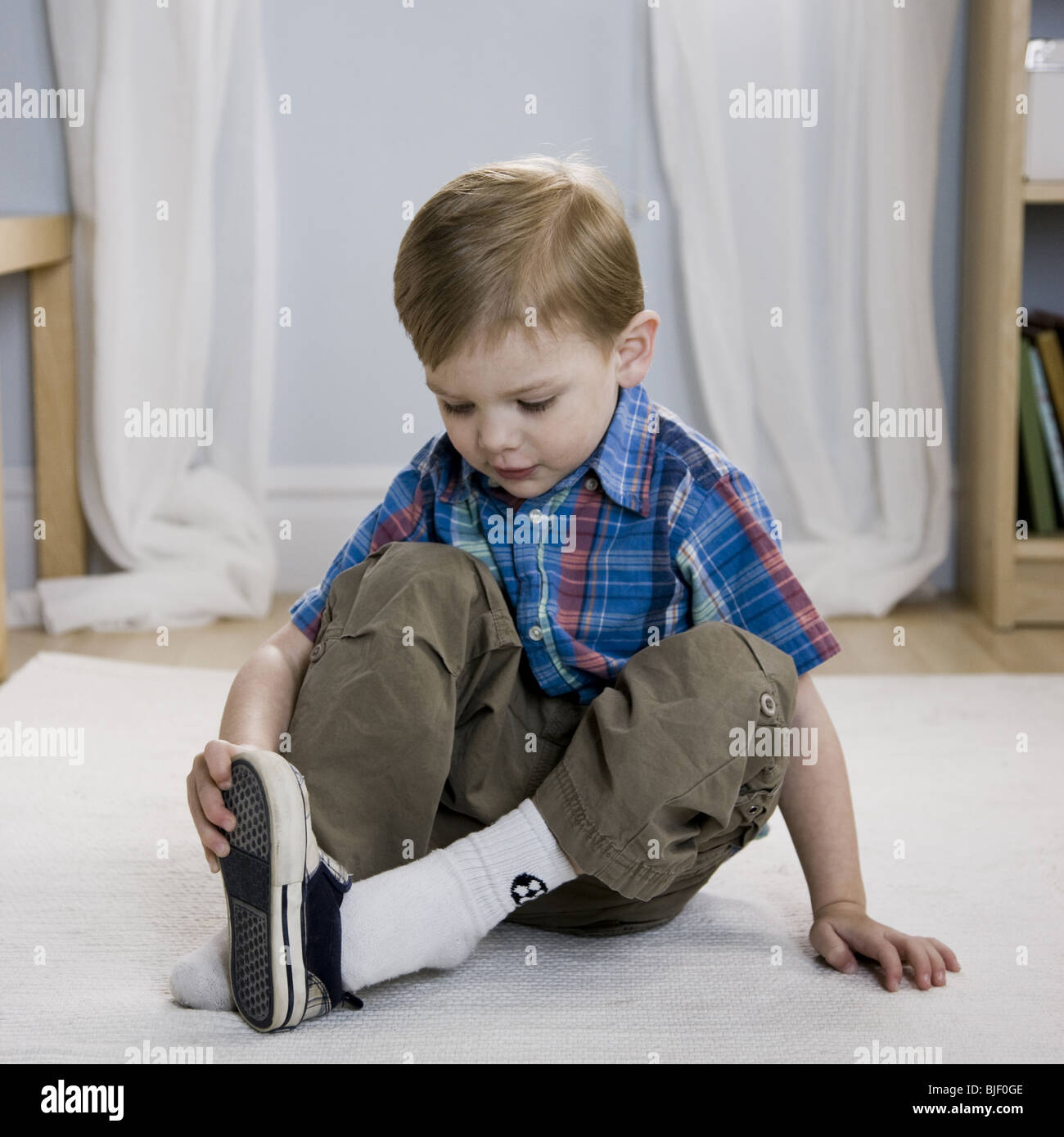 Beautiful Little Boy Takes Off Shoes While Sitting On A 